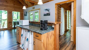 A kitchen with wooden cabinets, a granite countertop, a coffee maker, and a microwave. - Gorgeous View Cabin - in Red River Gorge, KY (Slade)