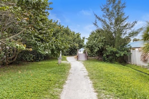 A pathway leading to a building surrounded by lush greenery and trees. - Siesta Beach House - 310 Come n' Beach It (Siesta Key)