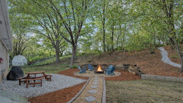 A backyard with a fire pit, seating, and a stone pathway.
