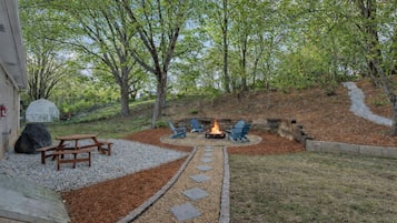 Un jardin avec un foyer, des sièges et un chemin en pierre.
