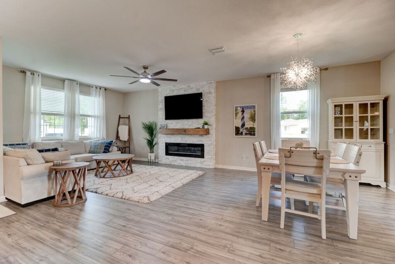 A spacious living room with a fireplace, a dining area, and a ceiling fan.