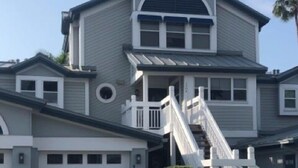 A two-story house with a front garage, a covered porch, and a staircase leading to the second floor. - Bayside Pointe 3 - 1302 (Siesta Key)
