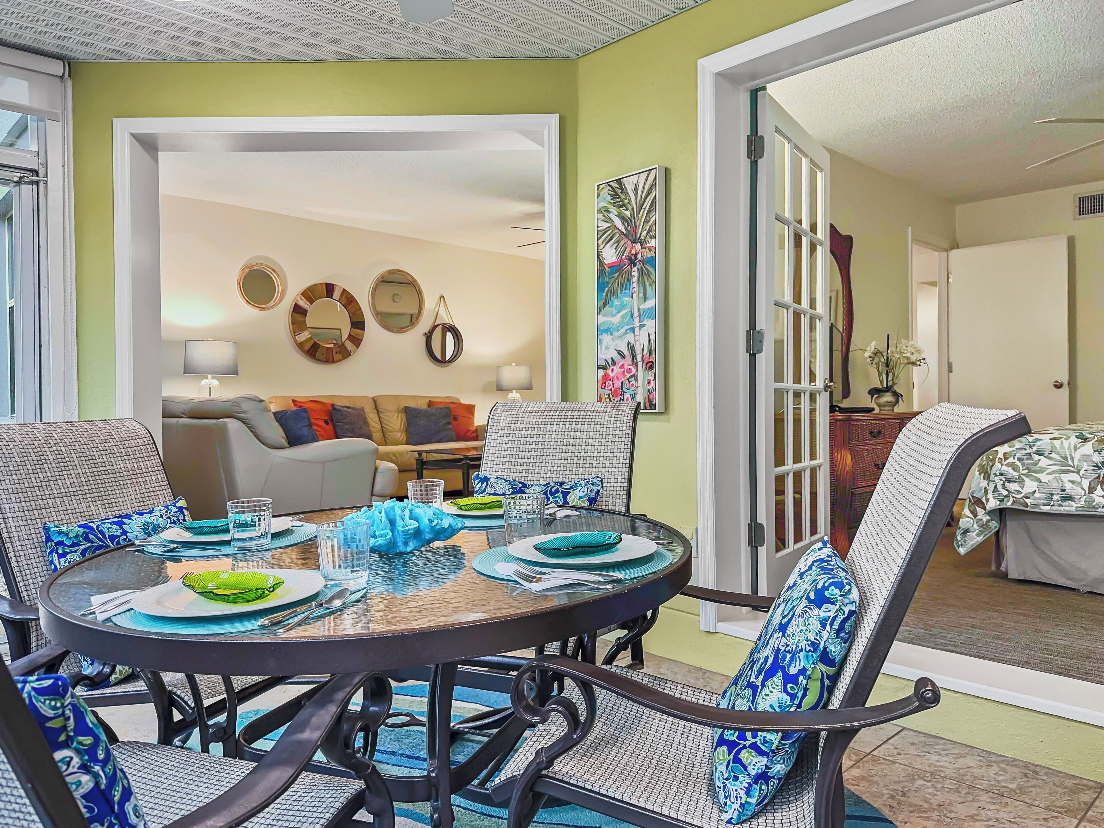 A dining area with a round table, chairs, and a view into a living room.