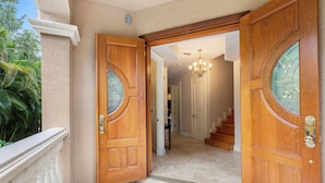 A grand entrance with two wooden doors, a marble floor, and a staircase leading to an upper level. - Miramar (Siesta Key)
