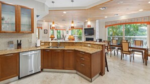 A modern kitchen with wooden cabinets, a granite countertop, and pendant lighting. - Miramar (Siesta Key)