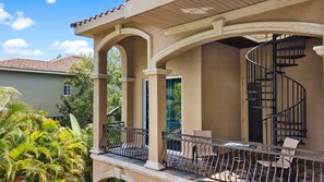A covered outdoor area with a spiral staircase, columns, and a railing. - Miramar (Siesta Key)