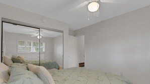 A bedroom with a bed, a ceiling fan, a closet, and a window with blinds. - Waterside Villa (Siesta Key)