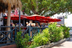 An outdoor restaurant with red umbrellas and a sign for 'S.K.O.3 Oyster Bar & Restaurant'. - Waterside Villa (Siesta Key)