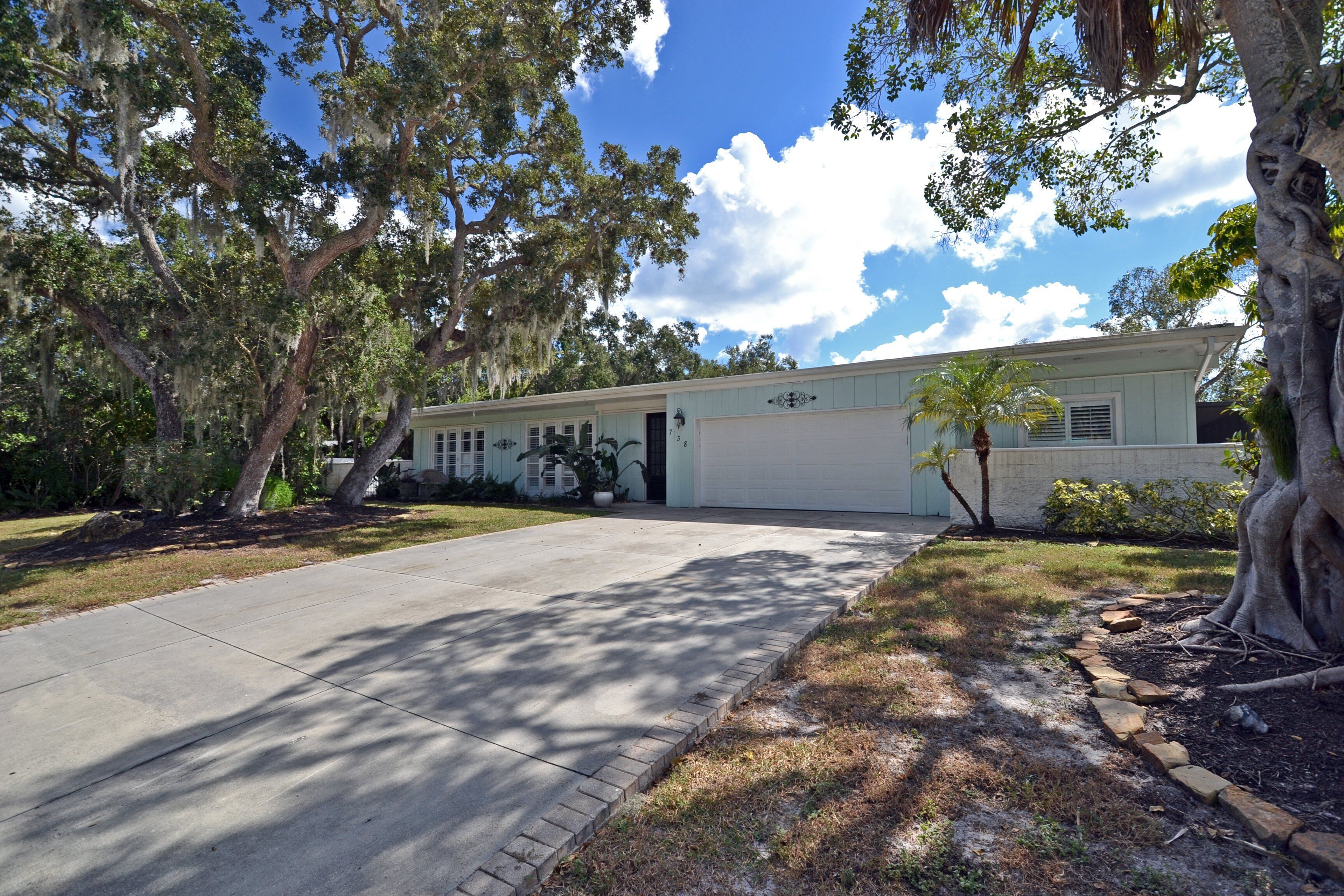 A single-story house with a garage, surrounded by mature trees and a well-maintained lawn.
