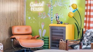 A room with a brown leather chair, a yellow radiator, and a wall with a 'Carousel House' sign. - Carousel House (Bend)