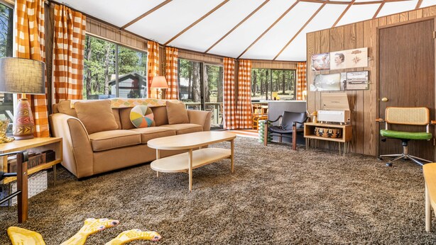 A cozy interior with a sofa, coffee table, and a desk area with a chair and lamp. - Carousel House (Bend)