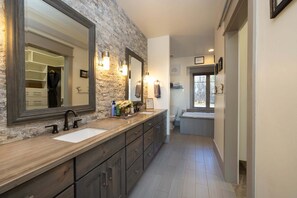 Un baño moderno con pared de piedra decorativa, un espejo grande y un vestidor.