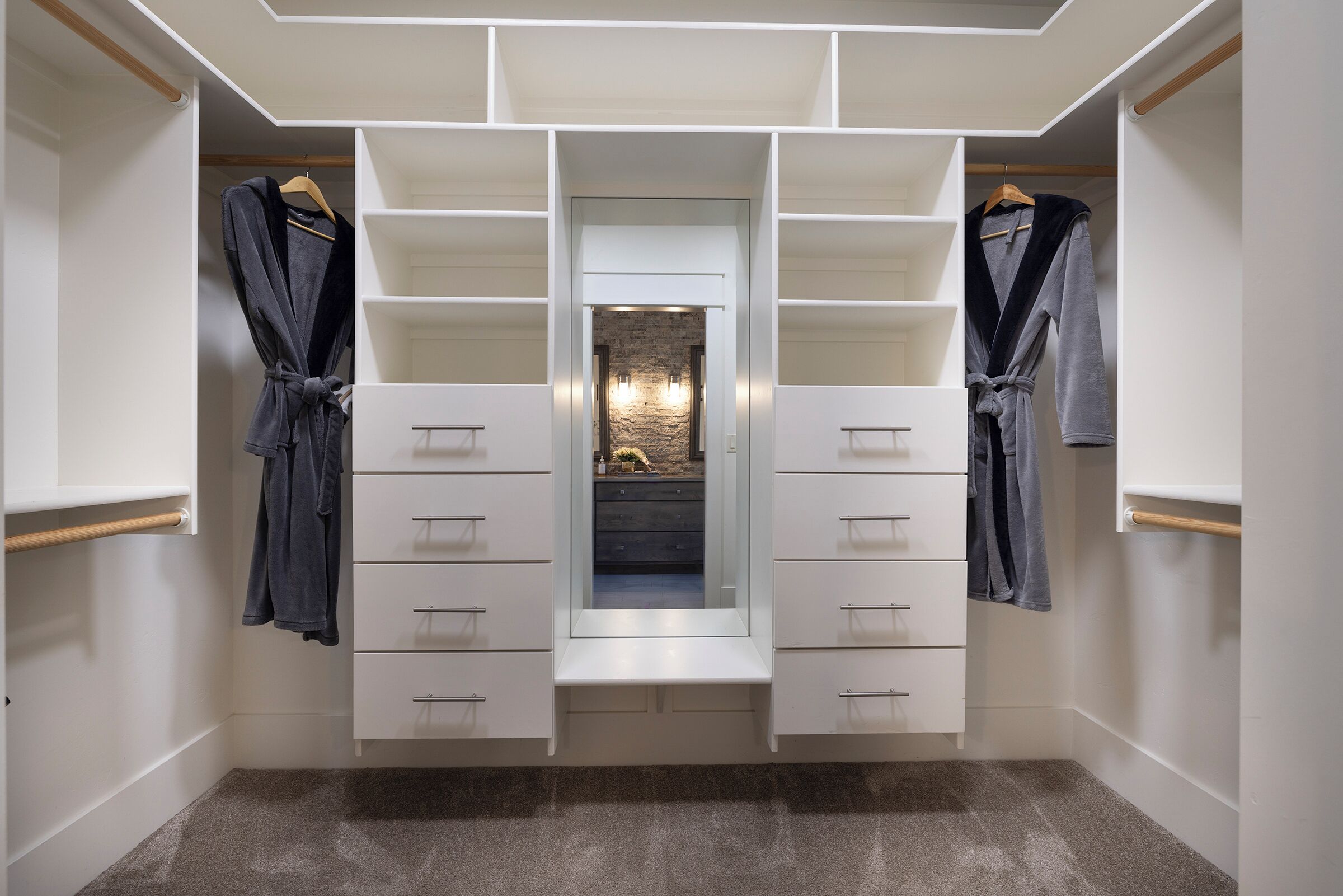 A walk-in closet with open shelving, drawers, and hanging robes.