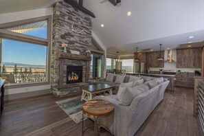 Un salón amplio con chimenea de piedra, un sofá grande y vistas a las montañas.