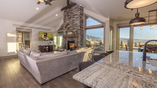 Un salón amplio con chimenea de piedra, ventanas grandes y un techo alto.