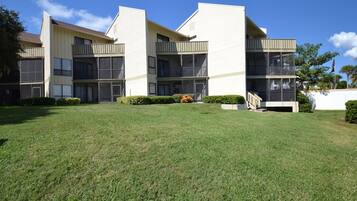 A multi-story building with balconies, a grassy lawn, and a white wall with an American flag.