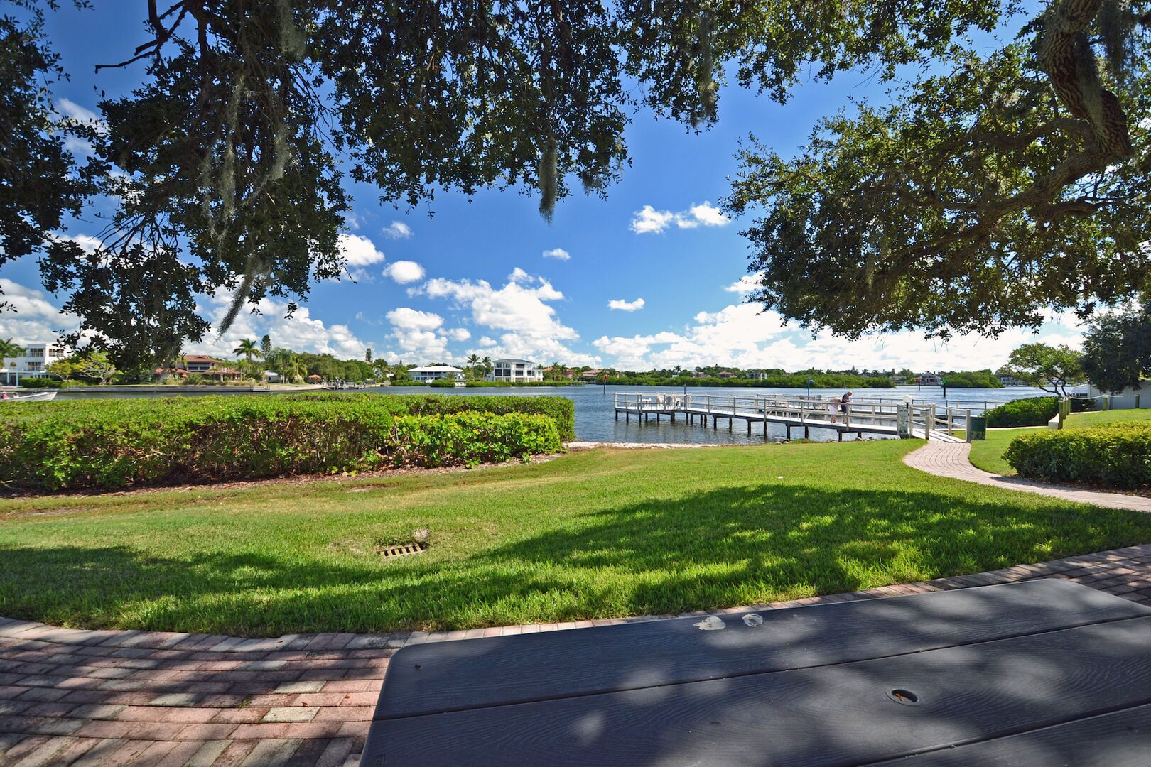 A park with a grassy area, a wooden deck, and a lake.