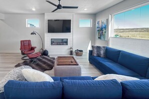 A modern living room with a blue sofa, red chair, and a flat-screen TV mounted on the wall. - Luxury Escape - Silver Creek (Park City)