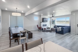 A spacious living area with a dining table, a sofa, and a TV mounted on the wall. - Luxury Escape - Silver Creek (Park City)