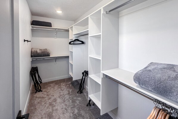 A walk-in closet with open shelving, a hanging rod, and a folded towel on the right. - Luxury Escape - Silver Creek (Park City)