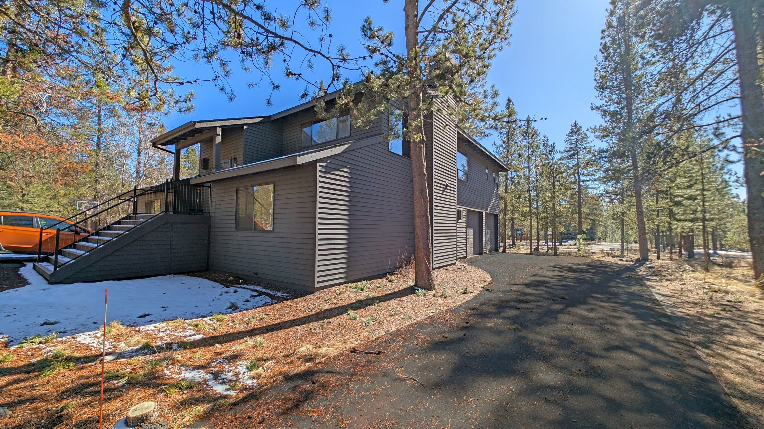 A two-story house with a covered porch, a staircase leading to the entrance, and a driveway.
