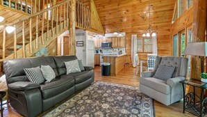 A log cabin interior with a staircase, a kitchen, two sofas, and a dining area. - Hot Tub & Wifi - Birdsong - Red River Gorge, KY (Stanton)