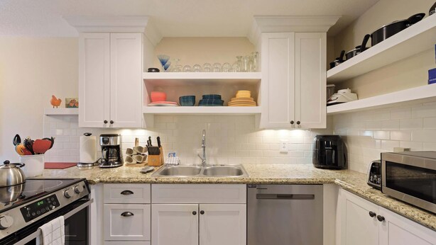 Une cuisine moderne avec des meubles blancs, une cuisinière en acier inoxydable, un lave-vaisselle et un four à micro-ondes.