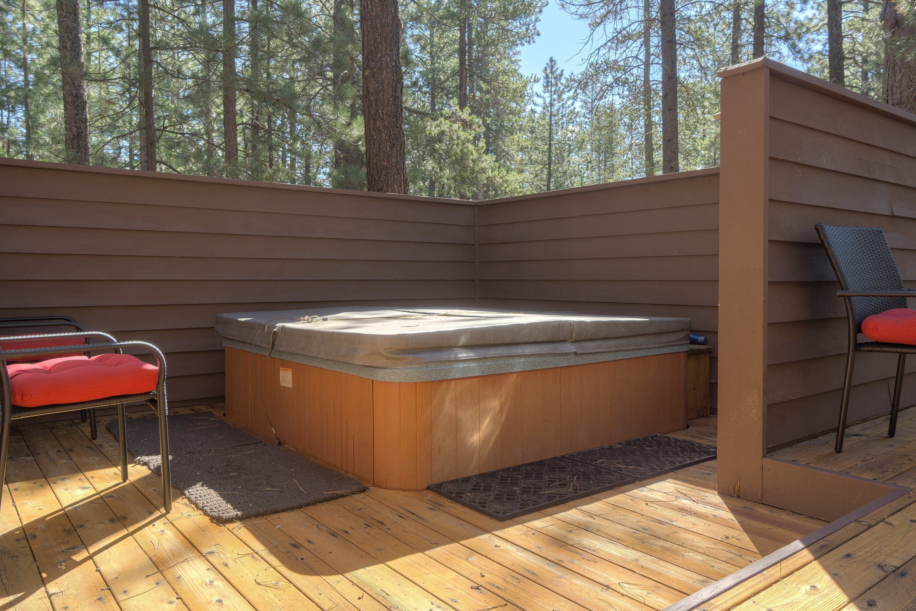 A hot tub on a wooden deck with a view of trees.