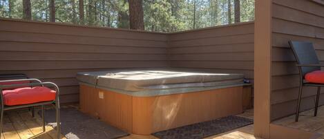 A hot tub on a wooden deck with a view of trees.
