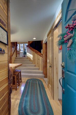 A wooden interior with a carpeted staircase, a dining area, and a blue door with festive decorations. - Diamond Peak 2 (Bend)