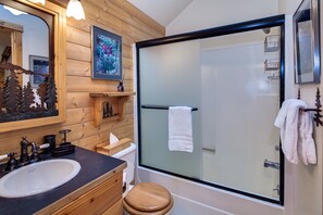 A bathroom with a wooden vanity, a sink, a mirror, a glass shower enclosure, and a towel rack. - Diamond Peak 2 (Bend)