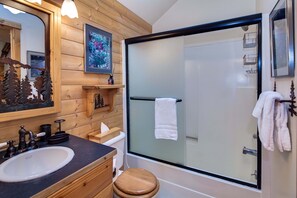 A bathroom with a wooden vanity, a sink, a toilet, and a glass-enclosed shower. - Diamond Peak 2 (Bend)