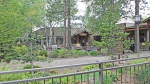 A lodge with outdoor seating, surrounded by trees and a garden. - 7th Mtn 1235a (Bend)