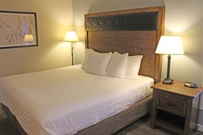 Una cama bien hecha con sábanas blancas, dos lámparas de noche y un cabecero de madera.