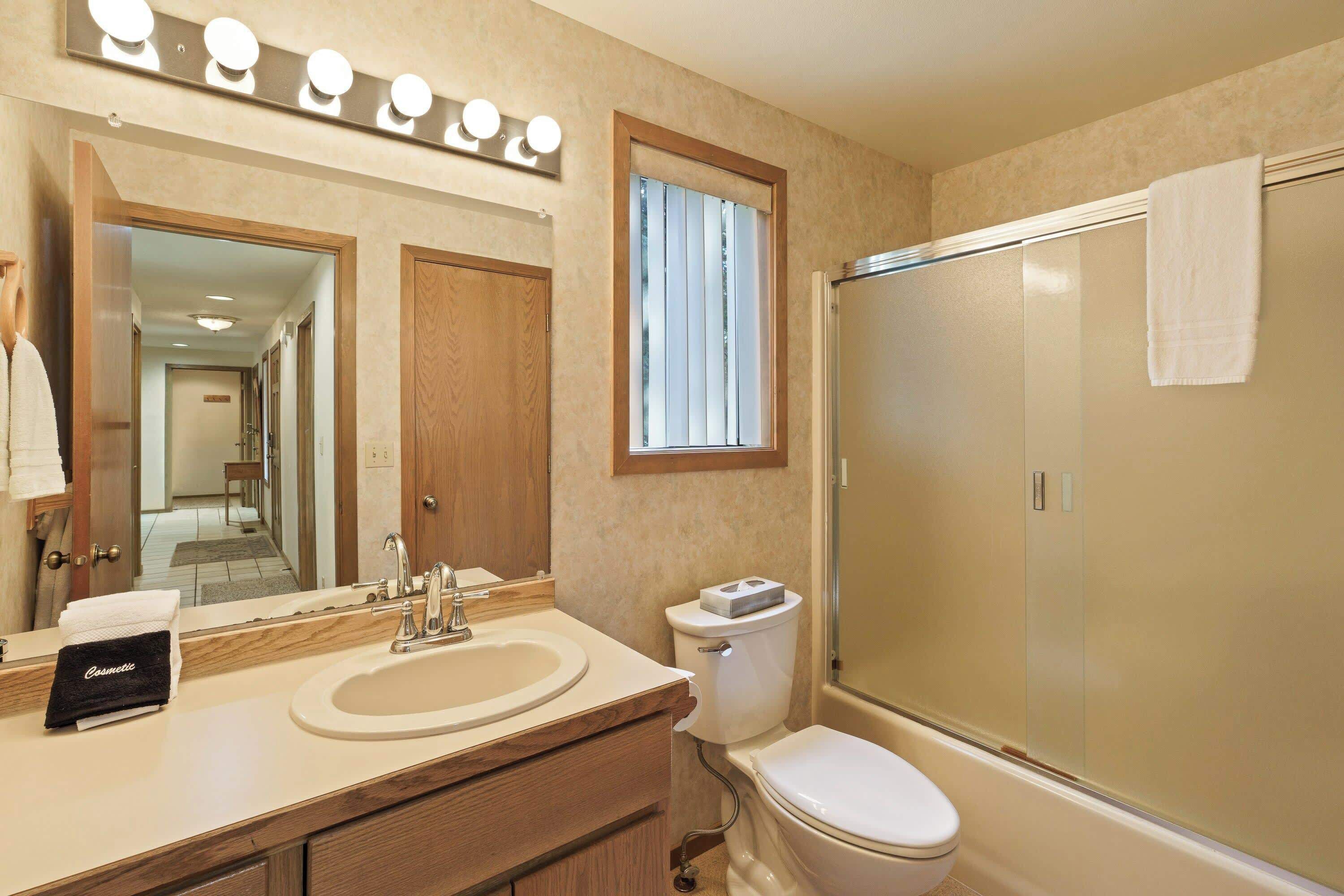 A bathroom with a sink, mirror, toilet, and shower.