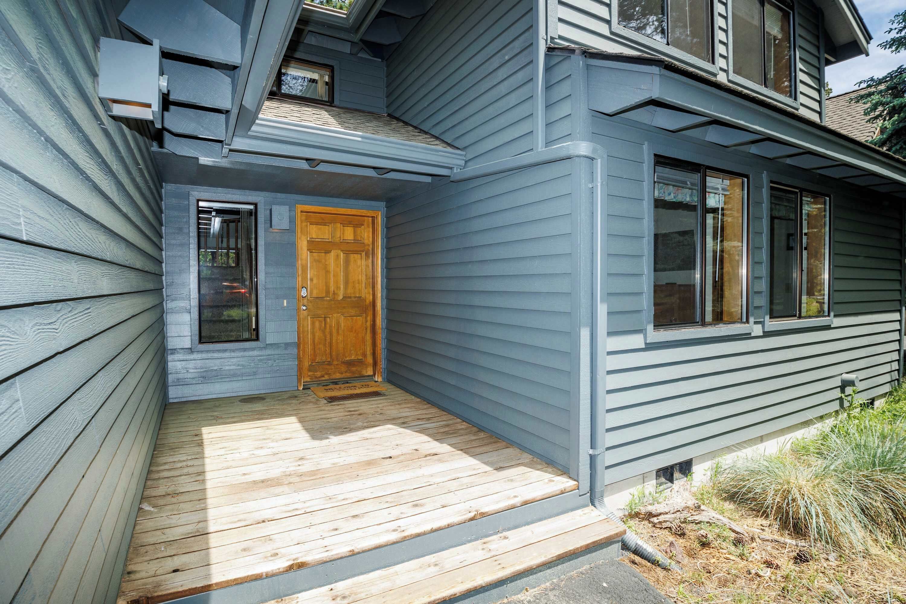 A house with a wooden front door, a covered porch, and a window.