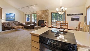 Uma sala de estar espaçosa com lareira, uma área de jantar e uma cozinha com fogão embutido.