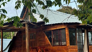 Une cabane en bois avec un toit en pente, de grandes fenêtres et une terrasse en bois.