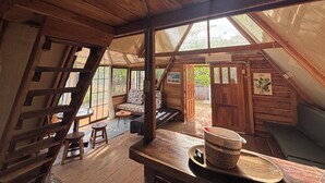 Une charmante cabane en bois avec une chambre à coucher en mezzanine, un coin repas et un petit porche.