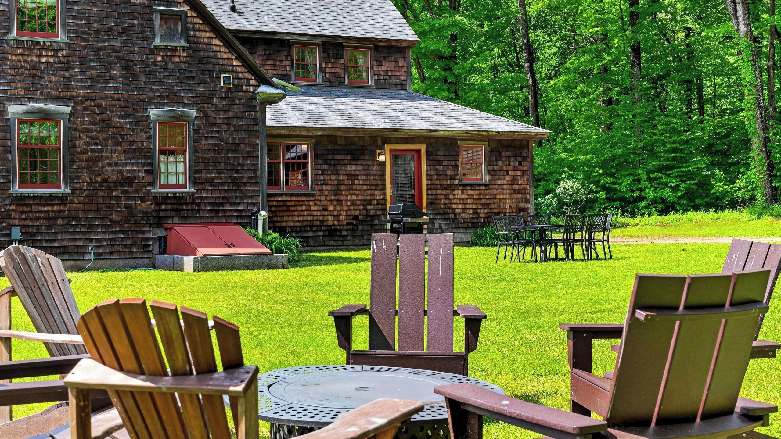 A log cabin with a front porch, outdoor seating, and a well-maintained lawn.