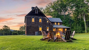 A large wooden house with a fire pit and chairs in the front yard. - 52-acre Berkshires Farmhouse Fire Pit, Outdoor Dining + Trails Copper Kettle Farm by Avantstay (Ashley Falls)