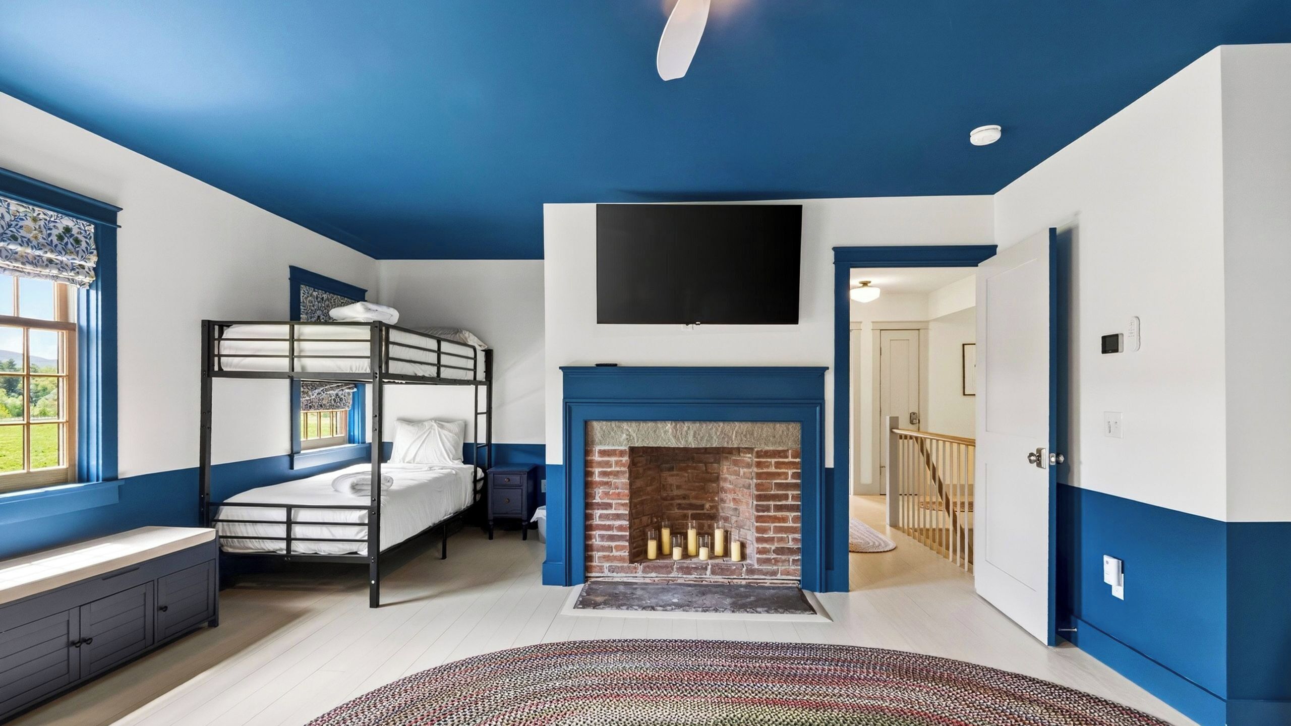 A room with bunk beds, a fireplace, a TV, and a view of the outdoors.