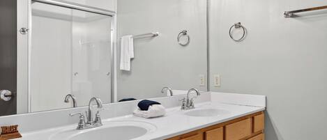 Une salle de bain avec deux lavabos, un miroir et un porte-serviettes.