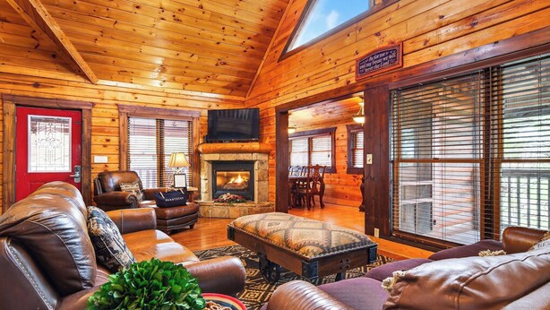 A log cabin interior with a fireplace, leather furniture, and a television. - Hot Tub, Game Room & Prime Pigeon Forge Location Big Bear Ridge by Avantstay (Pigeon Forge)