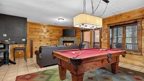 Egy hangulatos, otthonos belső tér, melyben biliárdasztal, kandalló, televízió és egy bár található.