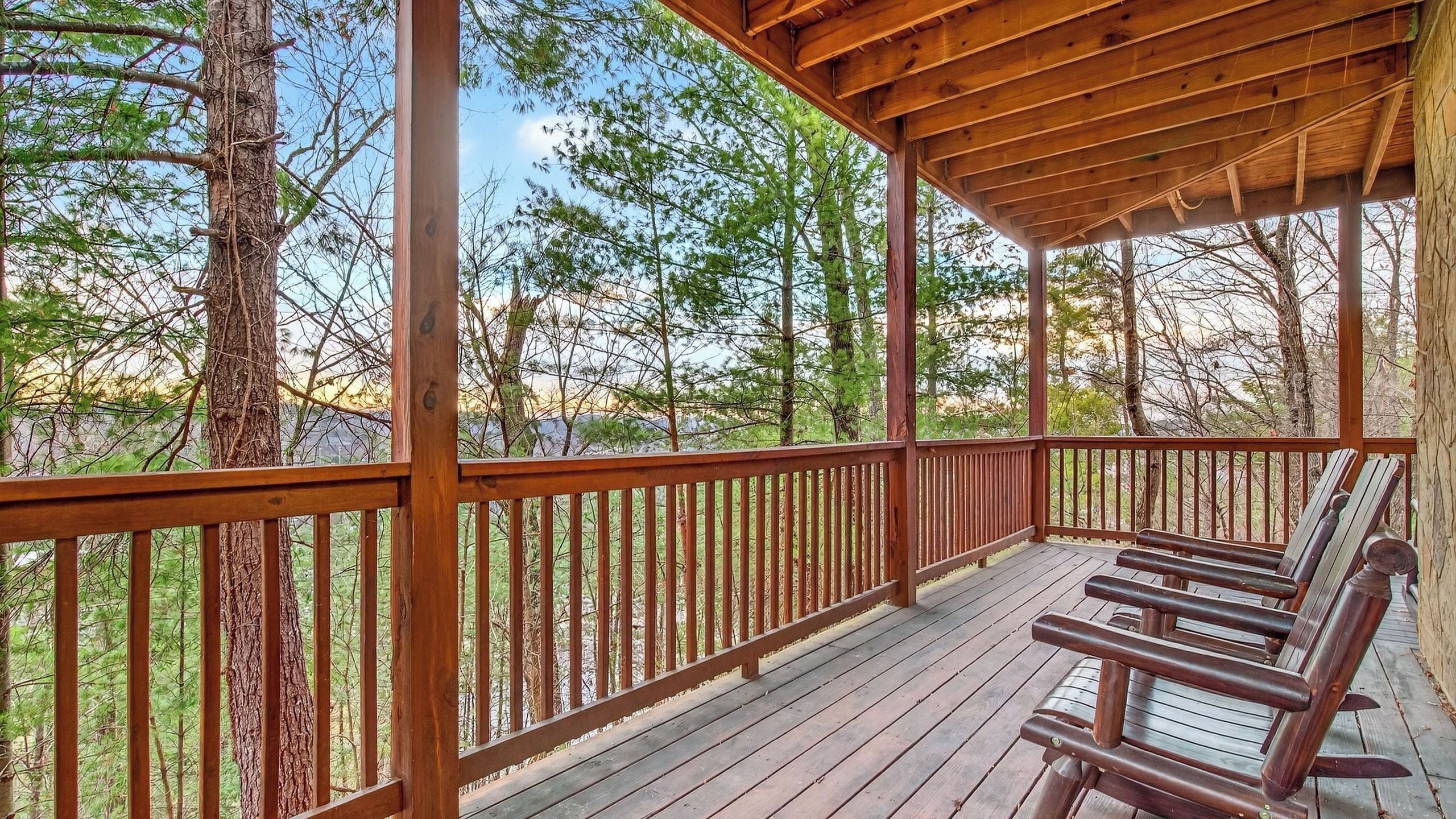 A wooden deck with benches, surrounded by trees.