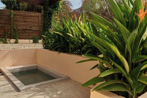 Ein Garten mit einem kleinen Pool, umgeben von üppigen, grünen Pflanzen und einem Holzzaun.