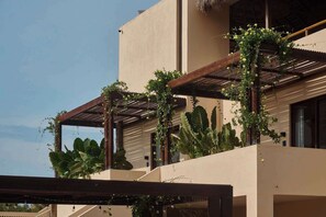 Un bâtiment moderne doté d’un toit plat, de grandes fenêtres et d’une pergola en bois recouverte de plantes grimpantes.