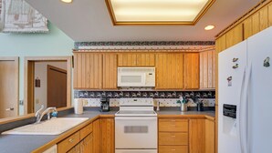 A kitchen with wooden cabinets, a white stove, a microwave, and a refrigerator. - Lake Access w/ Dock! Hayward Cabin Hideaway (Hayward)