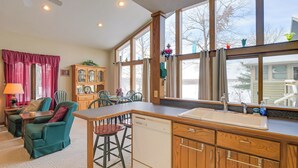 A kitchen with wooden cabinets, a dishwasher, and a large window. - Lake Access w/ Dock! Hayward Cabin Hideaway (Hayward)